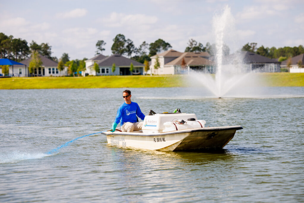 Man in a boat on a lake with a fountain in the middle.