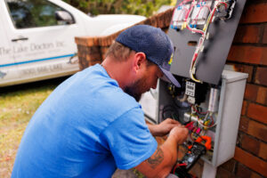 Man fixing something inside of an electrical box that controls a lake fountain.
