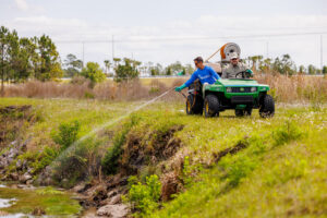 Man spraying water from a hose into a ditch